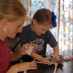 Woman and child doing crafts at table.