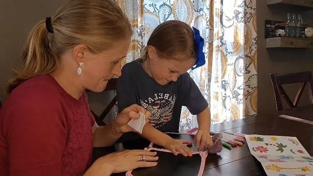 Woman and child doing crafts at table.